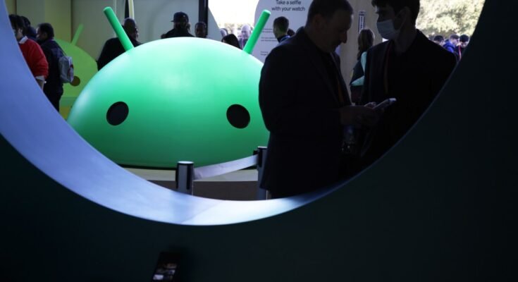 Attendees visit the Google booth where a model of the Android logo is on display at CES 2023 at the Las Vegas Convention Center.