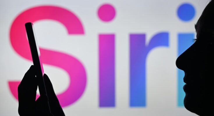 An image of a woman holding a cell phone in front of the Siri logo displayed on a computer screen.