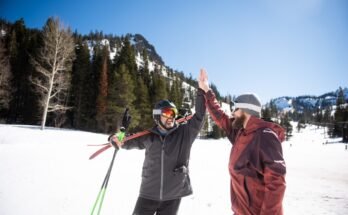 Two friends high-fiving while skiing.