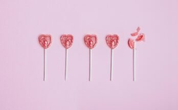 Five lollipop hearts on a pink floor, but the last one is smashed to pieces.