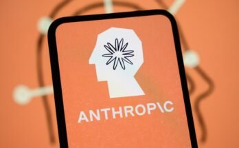The Anthropic logo is displayed on the screen of a smartphone with the company's branding in the background.