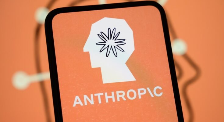 The Anthropic logo is displayed on the screen of a smartphone with the company's branding in the background.
