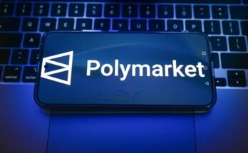 In this photo illustration, a Polymarket logo is displayed on a smartphone on top of a laptop.
