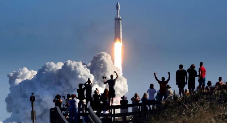 The crowd cheers at Playalinda Beach in the Canaveral National Seashore, just north of the Kennedy Space Center, during the launch of the SpaceX Falcon Heavy rocket, on Feb. 6, 2018.