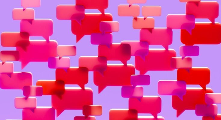 Conceptual image of a dense cluster of three-dimensional speech bubbles in shades of pink red and magenta overlapping and filling the visual field against a solid vibrant purple background.