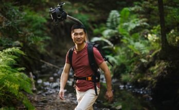 Man hiking in a forest wearing Odyssey camera pack