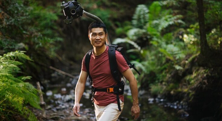Man hiking in a forest wearing Odyssey camera pack